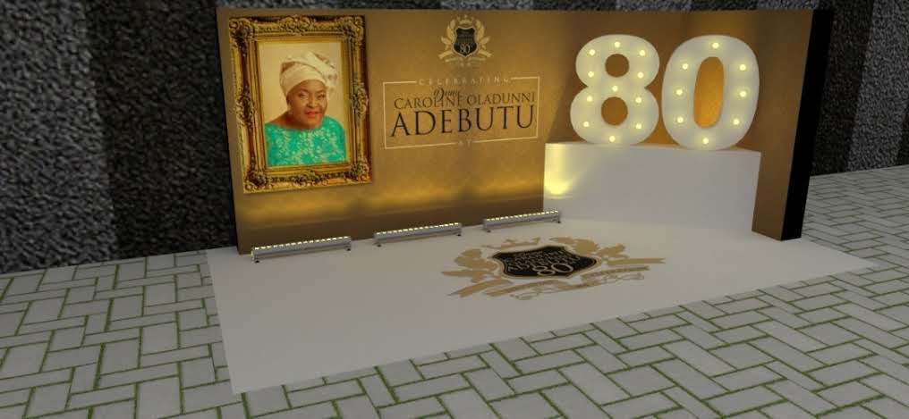 Illuminated celebration backdrop with a framed portrait of an elderly woman, text reading 'Celebrating Chief Caroline Oladunni Adebuto', and large lit-up '80' numbers on a pedestal.