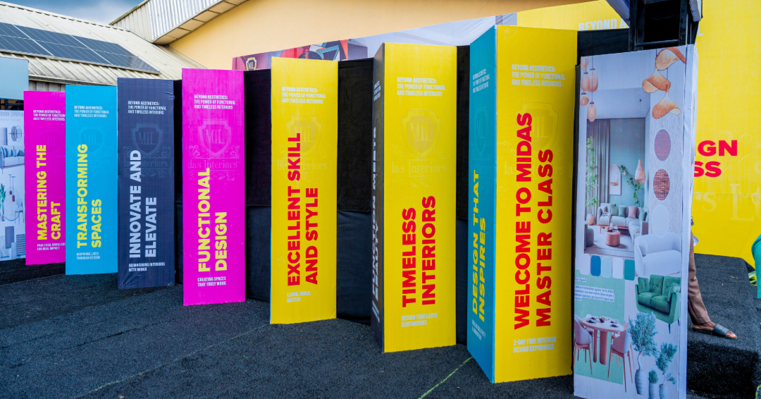 Colorful vertical banners standing outdoors on black pavement, each featuring text about interior design skills and master class themes.