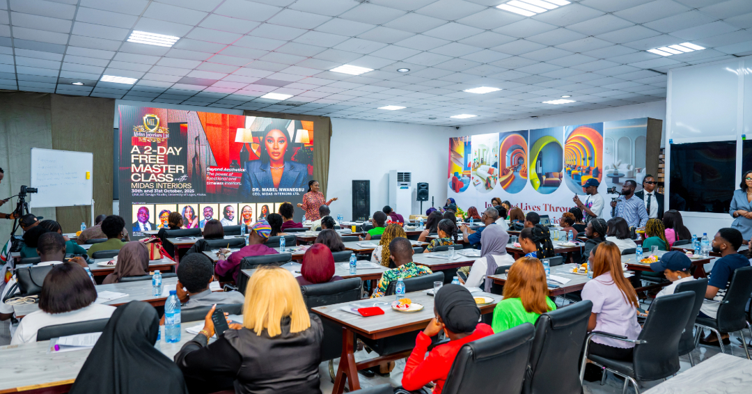A bright classroom filled with diverse adult students attentively attending a Midas Interiors 2-day free master class led by Dr. Mabel Nwannegbu, displayed on a large screen.